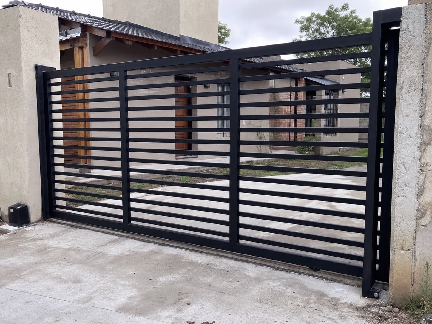 Portón corredizo de hierro negro instalado en frente de vivienda