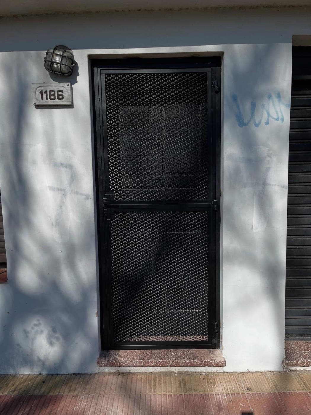 Puerta reja de metal desplegado negra a medida instalada en La Plata