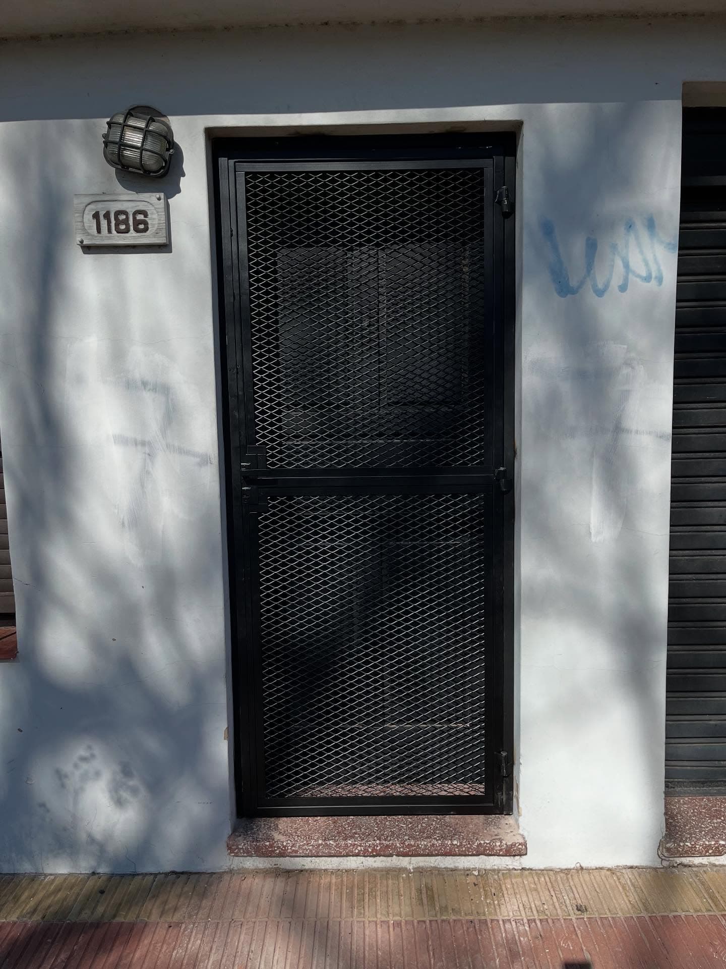 Puerta reja de metal desplegado instalada en acceso de vivienda